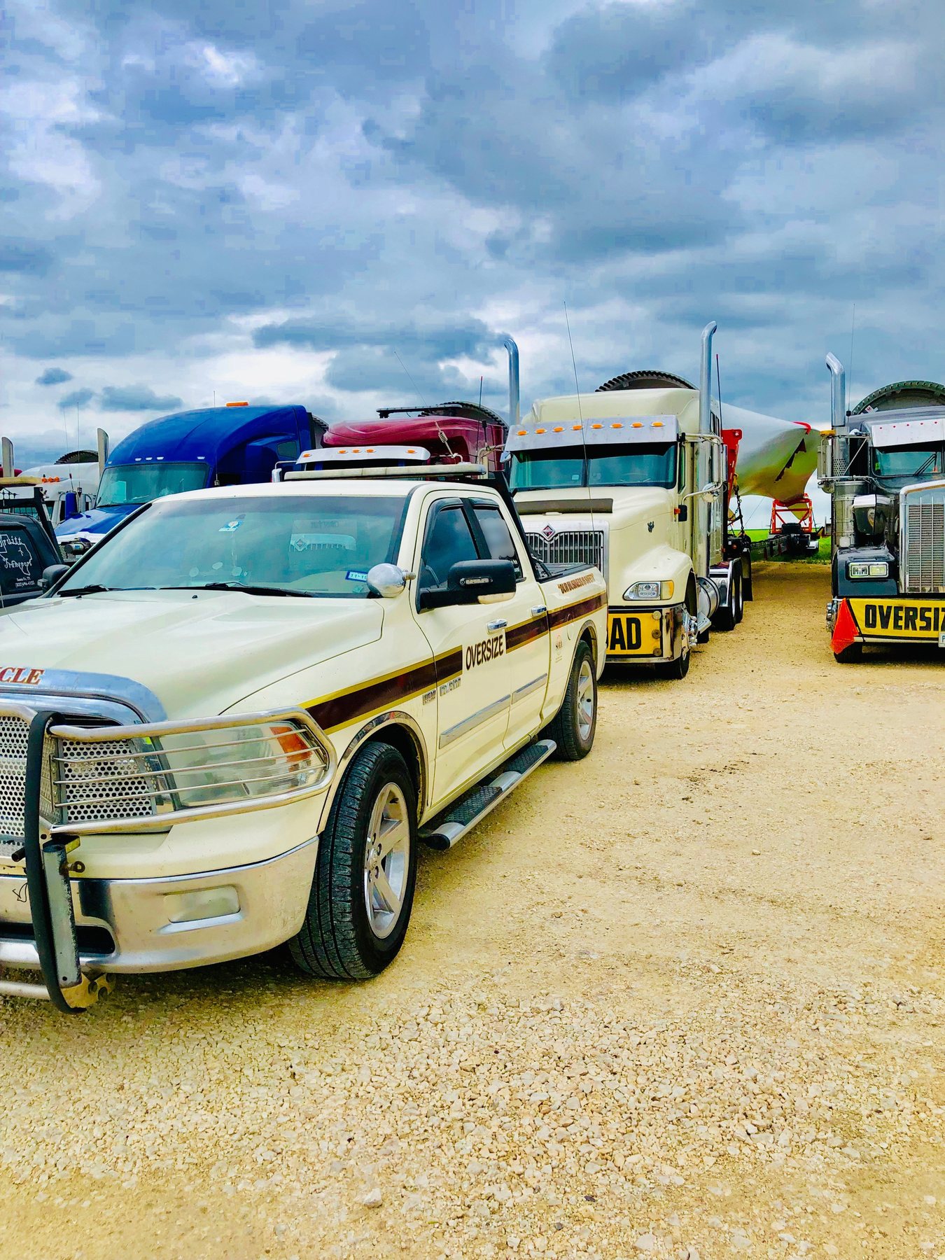Escort pickup staged with oversize tractors and a turbine blade