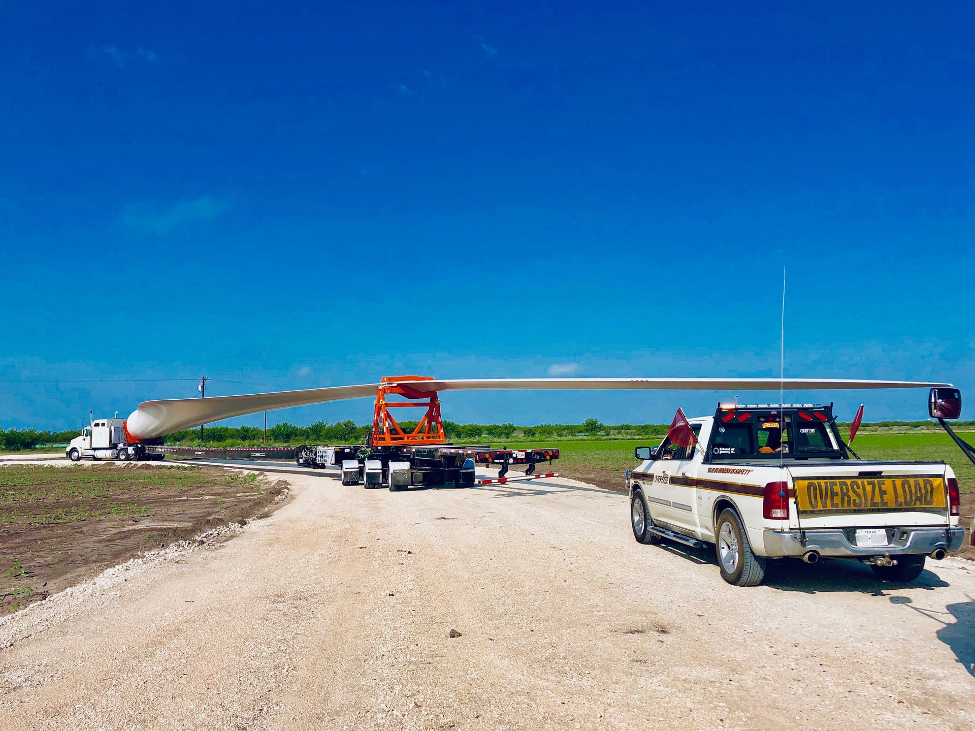 Oversize wind turbine blade on a Texas farm road with a Gracefull escort vehicle